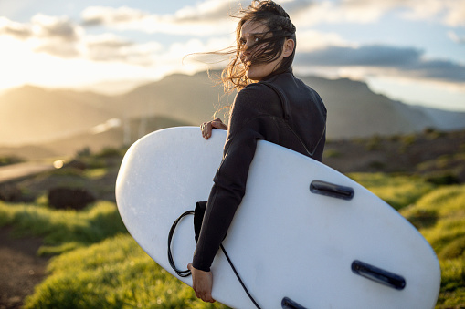 Middle aged woman goes surfing at sunset on an island. Getting away from it all.