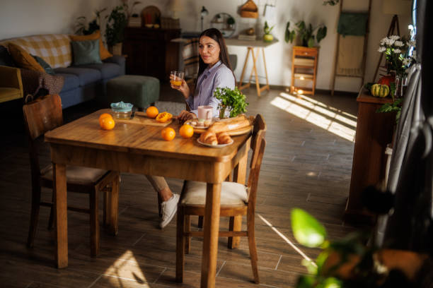 istock Woman sitting at dining table, enjoying fresh orange juice 2064280980