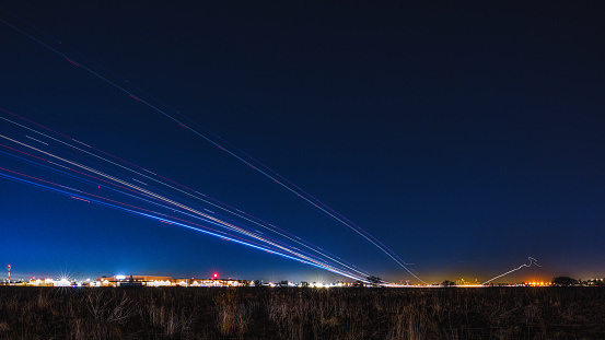 Night view of light trails from commercial aircraft departures at Pearson Airport.
