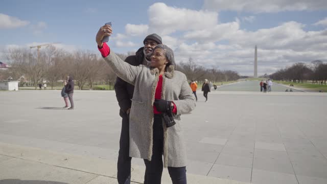 African American senior couple taking selfie photograph with Washington Monument in the background