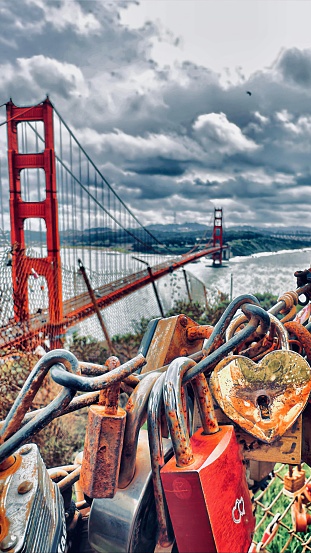 Collection of rusty locks on fencing in foreground, high angle view of Golden Gate Bridge in background. Hendrik Point Overlook, Marin Highlands, San Francisco, CA, USA.