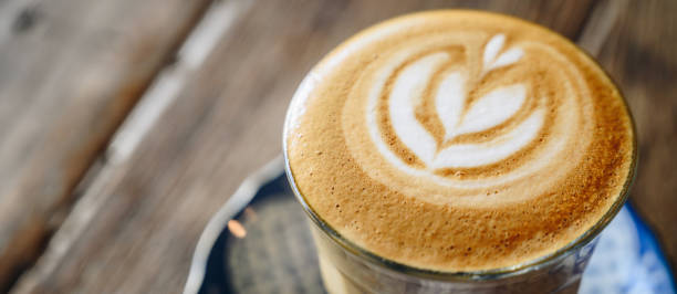 Close up of the surface of hot latte coffee on wooden table.
