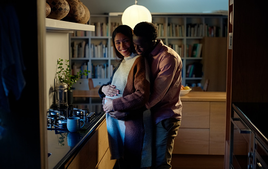 Love, pregnant and couple hug in a house with care, trust and hope for future family while bonding in a kitchen. Pregnancy, support and people embrace at home with gratitude, security or romance
