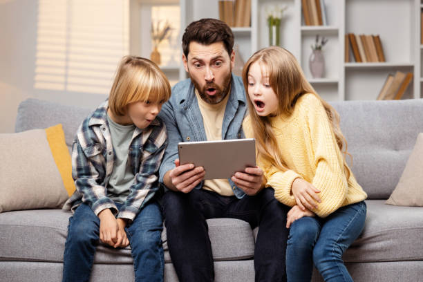 Surprised dad and kids looking at the tablet computer screen with astonishment