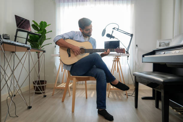 Handsome Caucasian man practicing playing guitar at home.