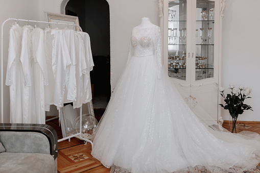 white identical women's outfit on a hanger. Women's robes. A girl's evening in the same outfit. An exquisite wedding dress with a long train on a mannequin in the bride's room