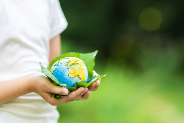 istock Kid holding small planet in hands against spring or summer green background. Ecology, environment and Earth day concept. 2064420612