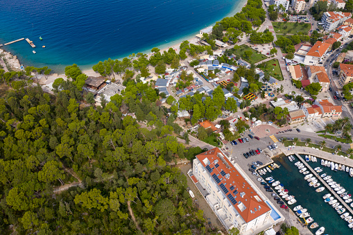Bird's eye view of the curved coastline and the city of Makarska. Croatia. Ships in the harbor, green forests,