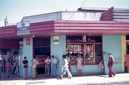 San José, Costa Rica, 1977. Street corner with locals and a grocery store.