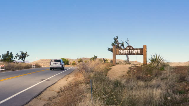 Pioneertown, California entrance sign with cars driving by