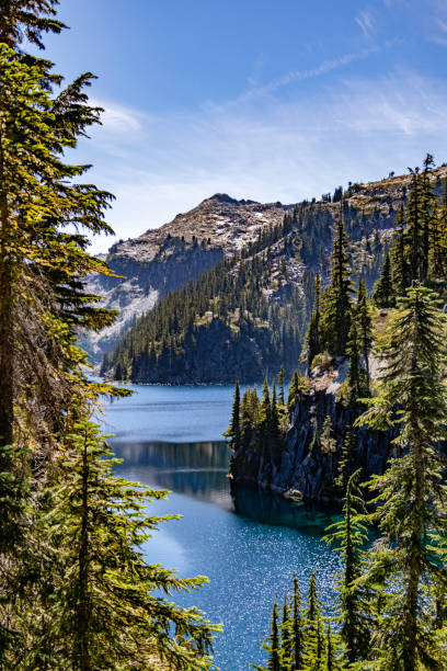 A high mountain lake ringed by cliffs and forest is seen through a break in the trees. Located in the central Cascades, Big Heart Lake is not easy to get to, but it is well worth the effort.