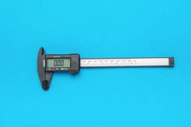 Photo of Electronic vernier caliper with zero readings on a blue background.