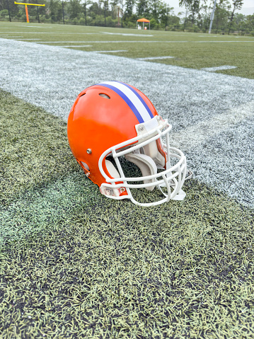 American football helmet in a practice field on a summer day