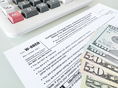 Tax forms and dollar bills with calculator on table top