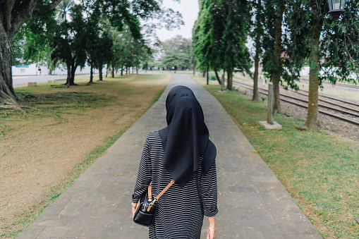 A muslim hijab woman walk alone at the street. View from the back or behind.