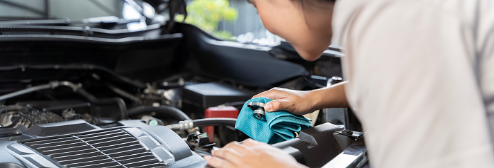 Check auto car's coolant level. That service, repair or maintenance by women hand to open cap of tank or reservoir for filling liquid cooled engine with water, antifreeze in radiator, cooling system.