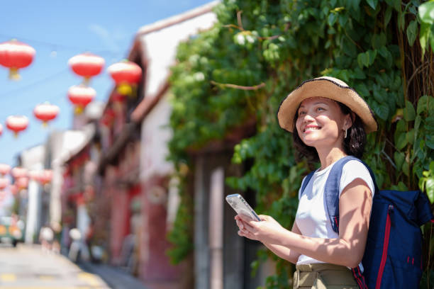 istock A solo Asian woman traveler, with a backpack and straw hat, uses her smartphone while exploring Georgetown, Penang. 2064831261