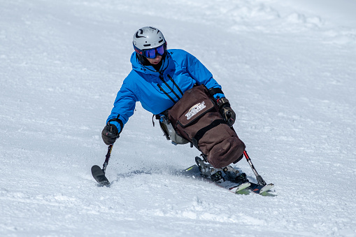 Vital senior, gray-haired men snow skier skiing, enjoying on sunny ski resorts. Skiing carving at high speed against blue sky.