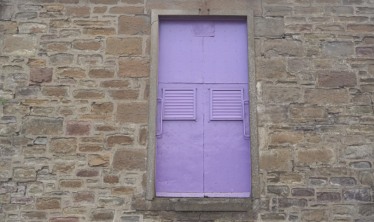 vintage purple industrial door in stone wall