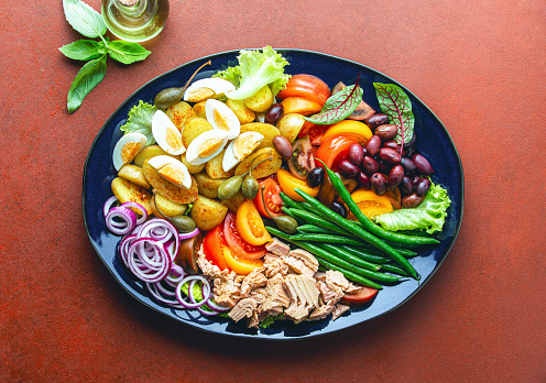 Healthy food well Known french cuisine recipe concept,  tuna Nicoise salad served in an oval blue dish, view from above