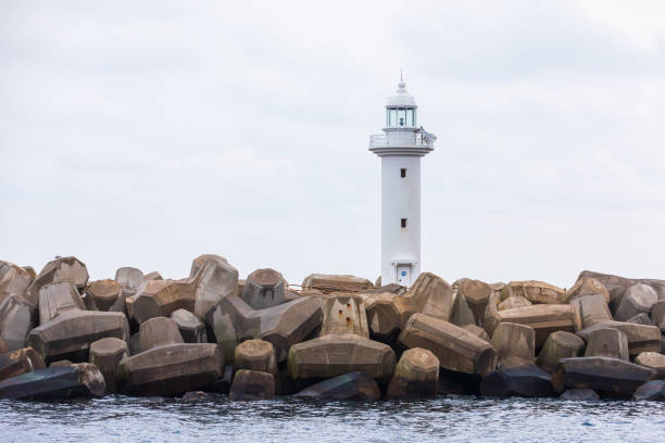White lighthouse on a breakwater surrounded by tetrapods.