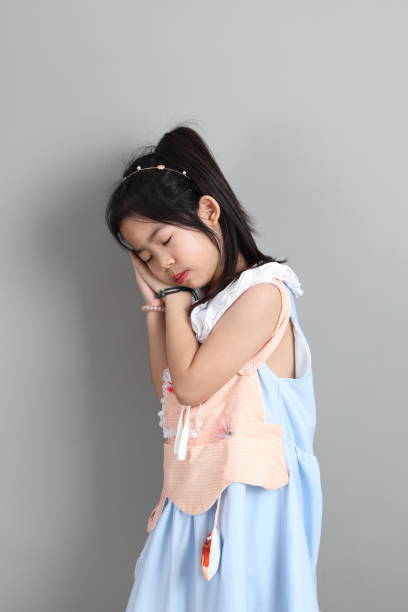 The little cut Asian girl with fancy dressed standing on the grey background.