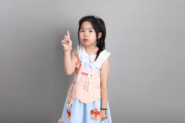 The little cut Asian girl with fancy dressed standing on the grey background.
