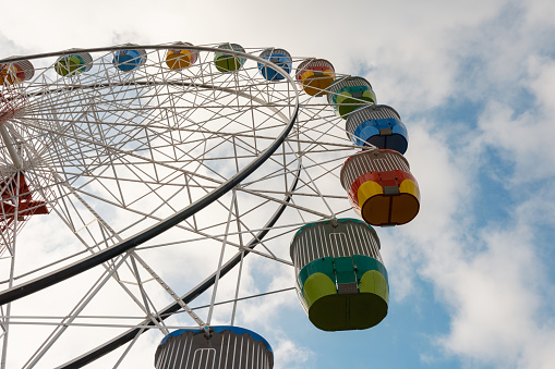 Looking up at part of a large Ferris wheel with dark clouds.