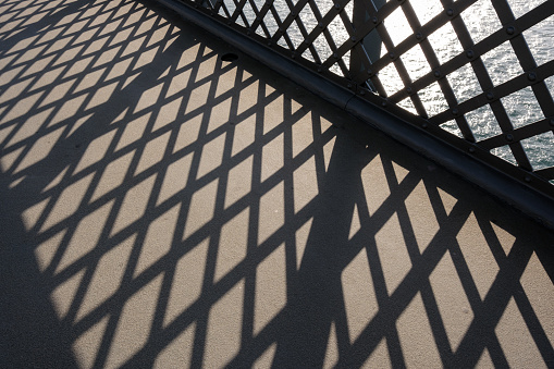 Shadow pattern on a concrete walkway from a metal fence.
