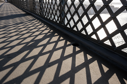 Shadow pattern on a concrete walkway from a metal fence