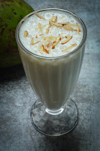 A tall glass filled with coconut milkshake.
