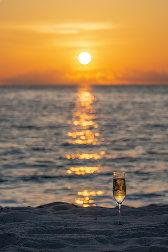 Wine glass half-buried in beach sand