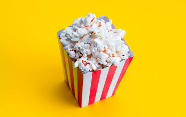 istock Popcorn in red and white striped paper box isolated on yellow background 2065075674