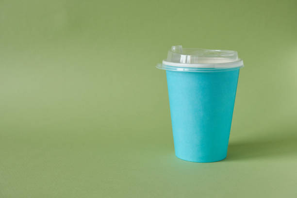 Blue paper coffee cup on green background. Copy space for text.