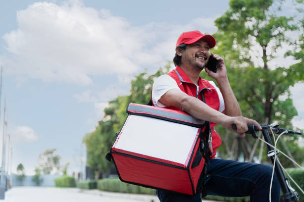 istock A delivery person riding a bicycle while using a smartphone. The person is wearing a helmet and a uniform. 2065156391
