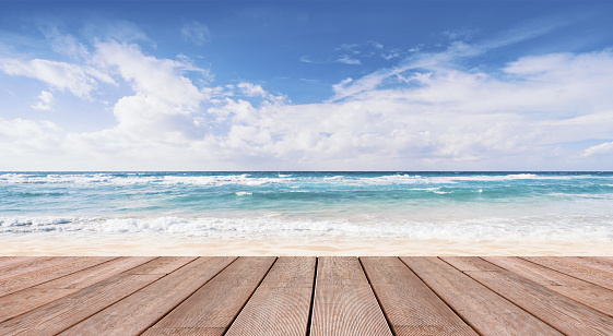 Empty natural summer beach view with ocean waves and wooden deck in the foreground, summer vacations background
