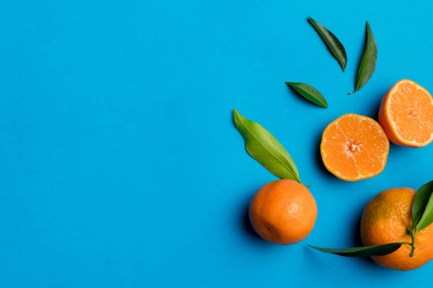 istock Many fresh ripe mandarin with green leaves on colored background, top view, space for text 2065177321