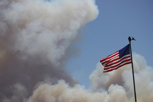 Flag on pole with thick smoke in background