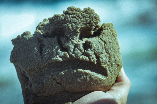 Close-up of a person holding an object in sandy terrain