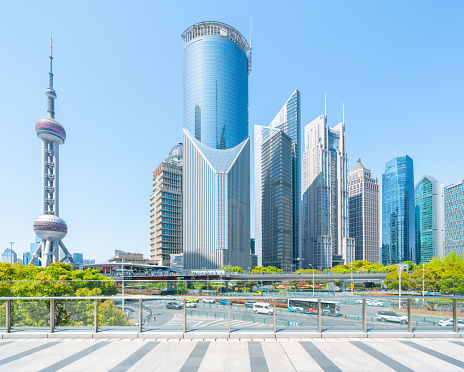 Shanghai, China - April 5th 2021:Financial buildings of Lujiazui, people walking on the pedestrian bridge in sunny day