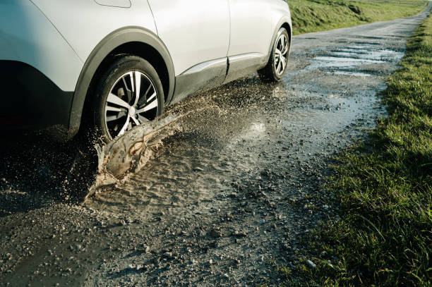 car hitting a pot hole and splashing - pot hole street car hole photos et images de collection