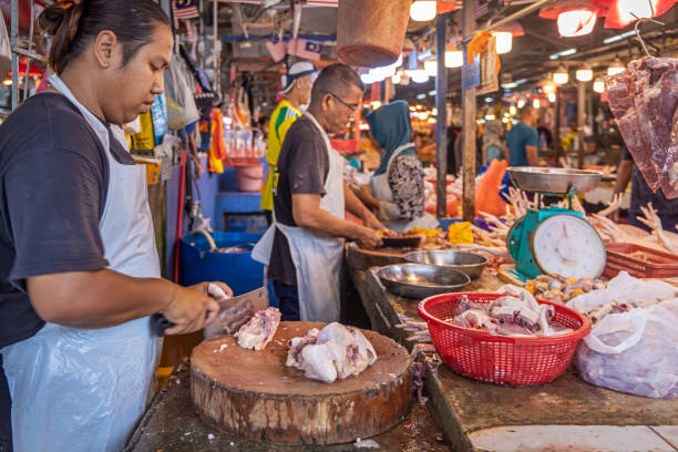 Chow Kit market, Kuala Lumpur, Malaysia - January 5th 2024: Men cutting up beef meat for sale at a butcher's shop at the central food market