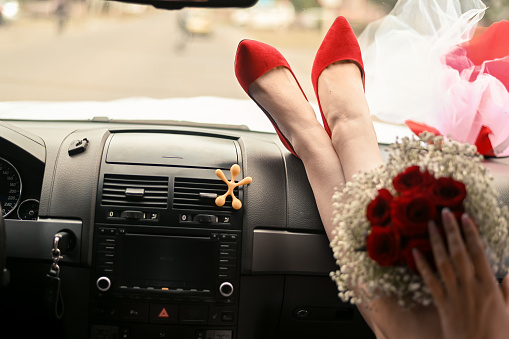 the bride with her feet in red shoes on the dashboard of the car.