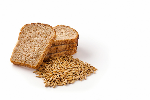 Slices of grain bread and wheat grains on a white isolated background. Healthy food concept.