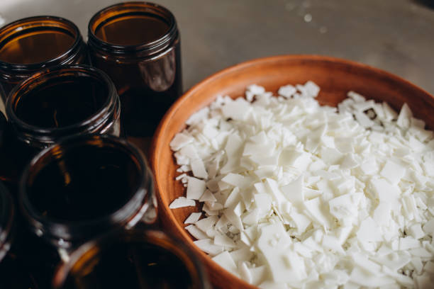 bougies opaques et ambrées, avec mèche en bois, prêtes à fabriquer. la cire de soja n’est pas fondue dans un bol en verre, avec une cuillère noire. produit végétalien sans cruauté envers les animaux. - cire de soja photos et images de collection