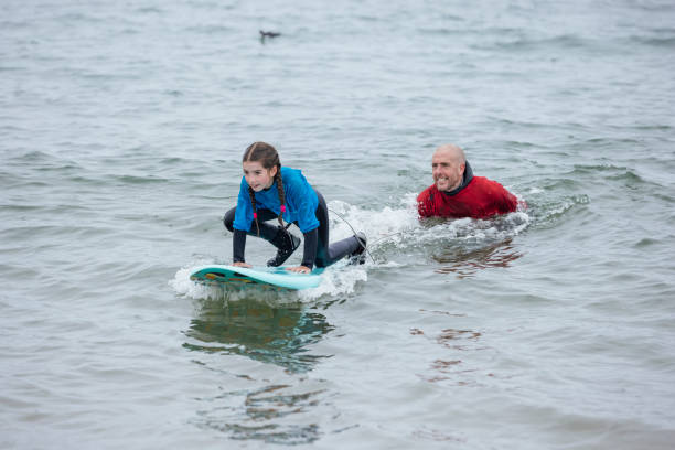 empujando hacia arriba en la tabla de surf - surfing role model learning child fotografías e imágenes de stock