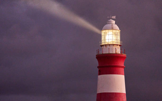 Lighthouse Punta de Teno on the Atlantic Ocean - Tenerife. Rocky Coast With Lighthouse, crepuscular rays, sunlight coming from the clouds. Canarian Island / Spain