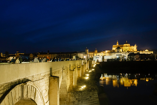 People strolling on the Roman bridge of Cordoba dating back to the early 1st century BC, that crosses the Guadalquivir river and leads to the town center; it is a Unesco World Heritage Site