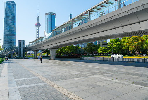 Shanghai, China - April 5th 2021:people walking on the pedestrian bridge, bus and car driving on asphalt road,sunny day