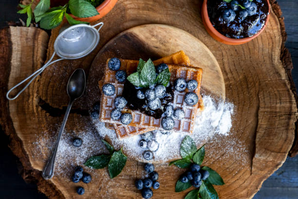 Waffles with fresh blueberries and powdered sugar on the rustic table. Freshly baked Belgian waffles